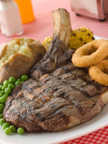 A large steak dinner, showing the need in the U.S. for a doggy bag for restaurant leftovers. Different cultures have different size portions. (Image © Monkey Business Images.)