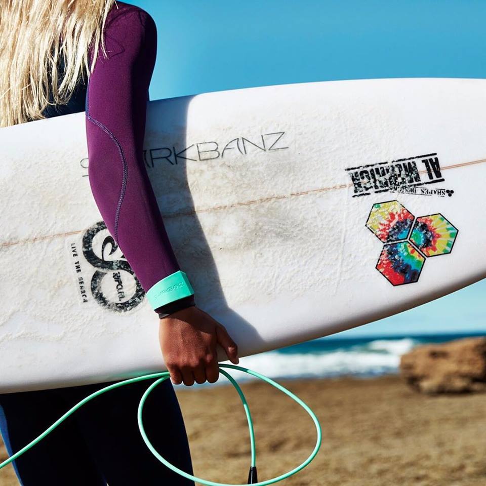 A woman surfer wearing a shark repellent bracelet, showing the invention of creative thinkers (image © Elyse Lu).