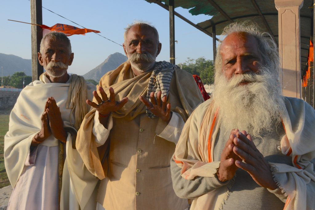 Three Hindu pilgrims at Pushkar Lake in Rajasthan, India, a place for travel adventures. (Image © Meredith Mullins.)