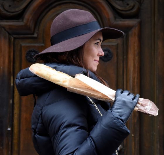 Young woman carrying baguette on her shoulder, proper baguettetiquette, an invented word in French language as part of wordplay. (Image © Meredith Mullins.)