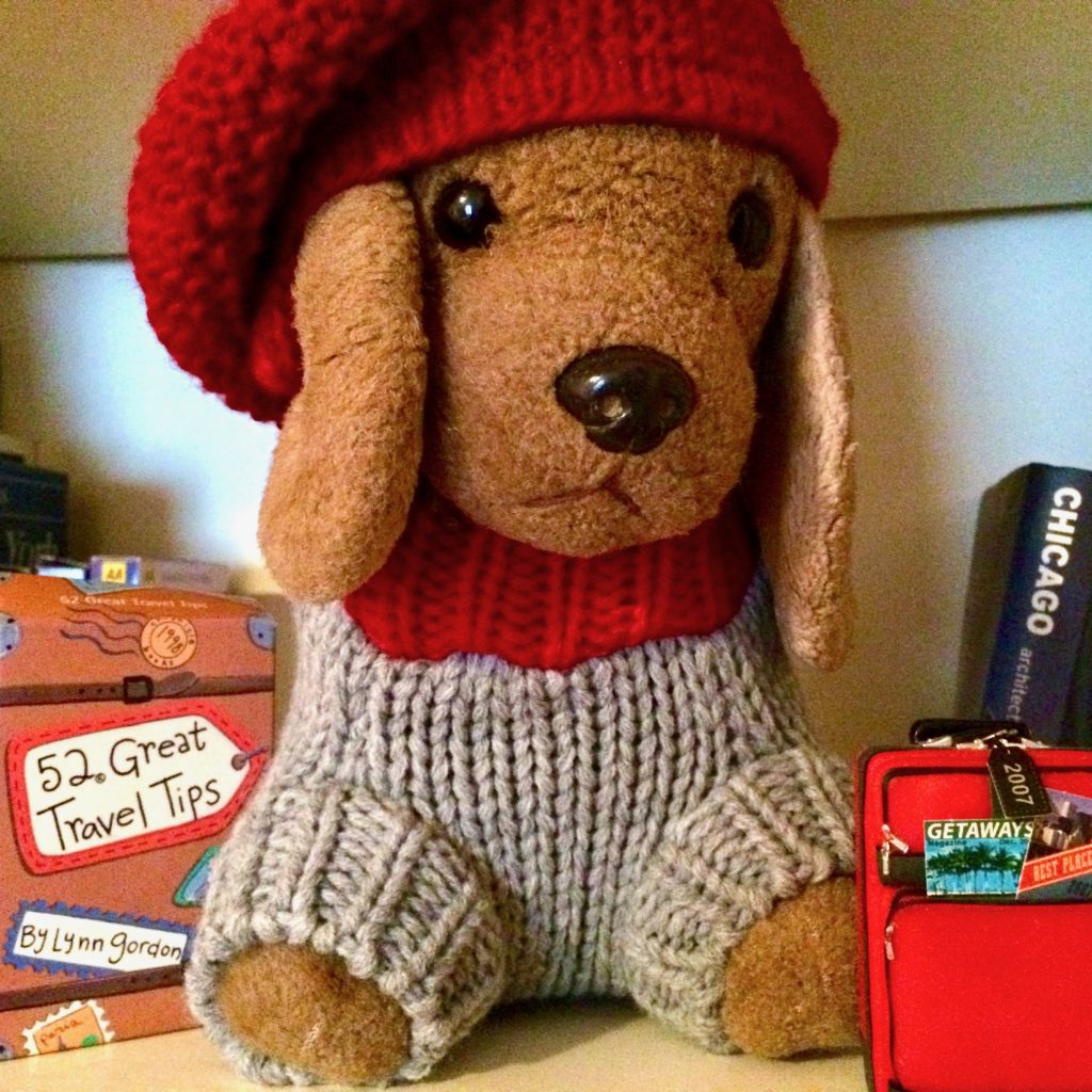 A toy canine travel mascot named Bedford, shown with tiny travel gear, inspires his human travel buddy to see the world differently. (Image © Joyce McGreevy)