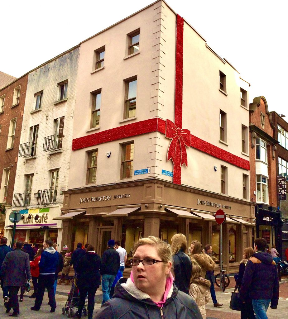 A "face in the crowd" in Dublin, Ireland and a gift-wrapped building evoke the need for the Irish tradition of the party piece, sharing songs, stories, and poems. (Image © Joyce McGreevy)