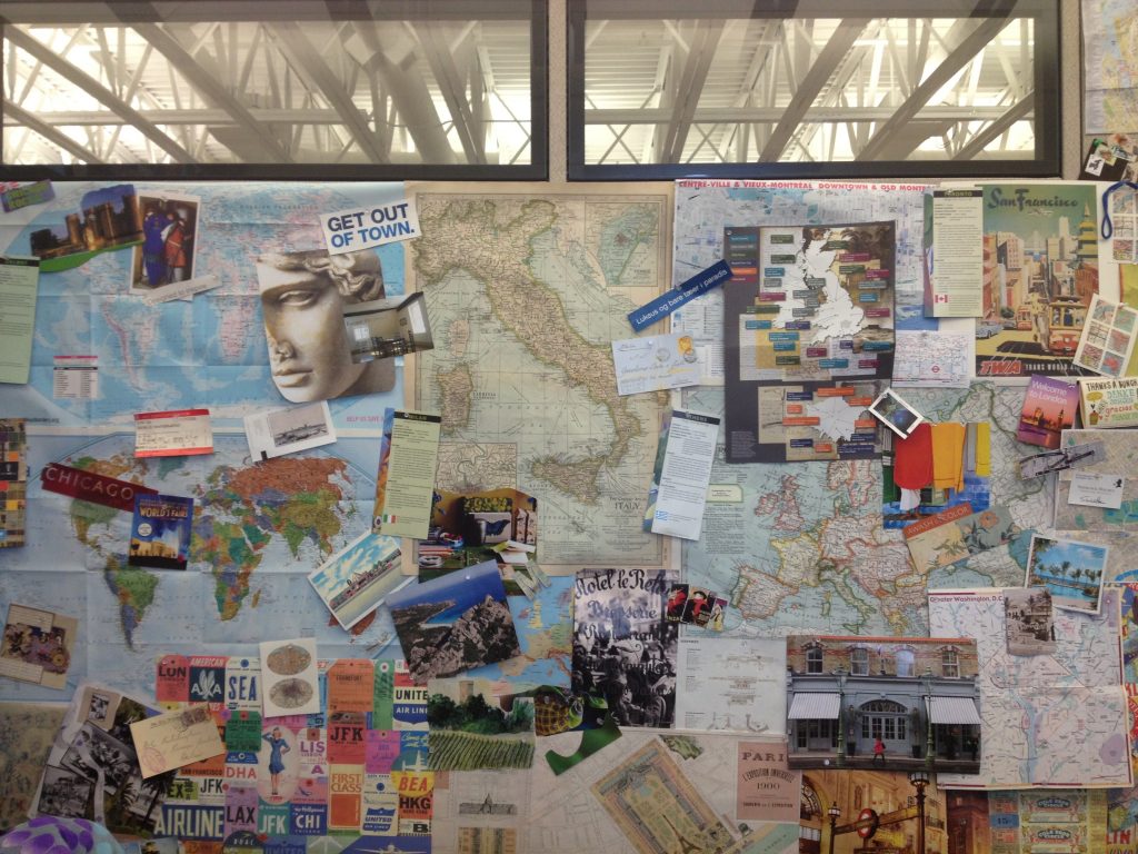 A collage made of travel ephemera on an office wall in Chicago leads a writer to ponder ways people find travel inspiration in souvenirs. (Image © Joyce McGreevy)