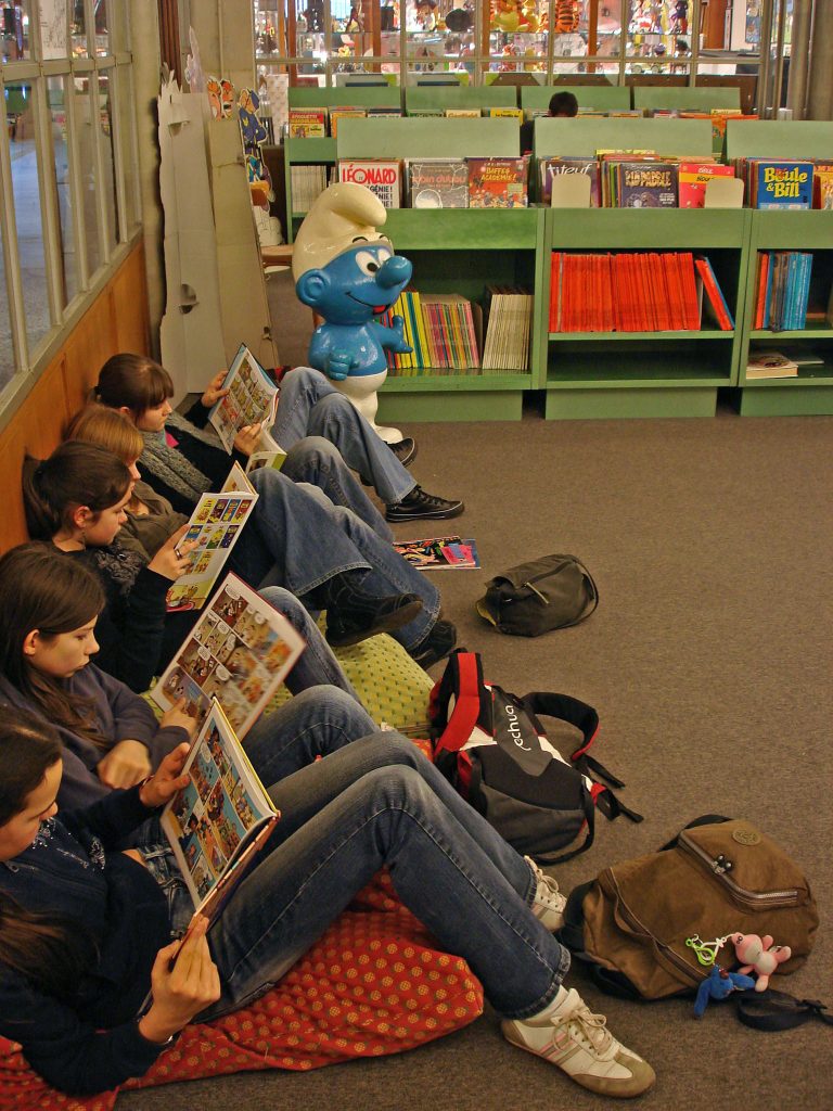 A group of children intently reading comic books at the Belgian Comic Strip Center show why comic books are a popular cultural tradition in Belgium. (Image © www.visitbrussels.be and Daniel Fouss)