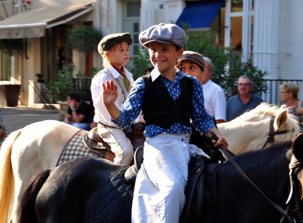 Boy on horseback waving in parade celebrating French cultural heritage and traditions