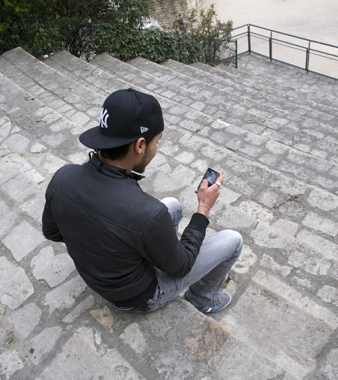 Young man texting in the Arenes de Lutece, a cultural experience that mixes old and new.
