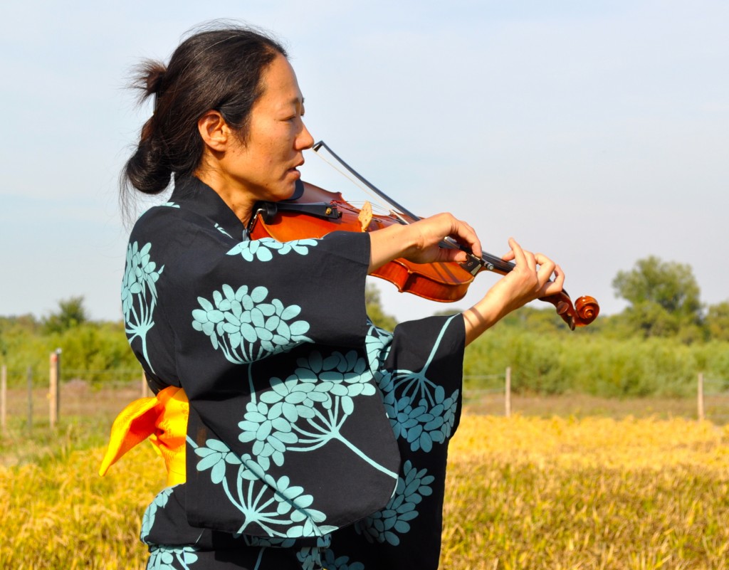 Violinist playing by the French rice paddy art, and providing creative inspiration for the harvest. (Image © Sheron Long) 
