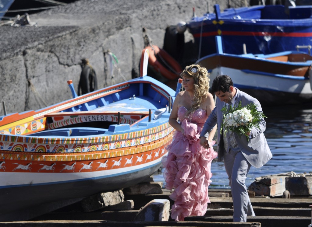 Newly-married couple pose by a traditional Sicilian boat reflective of the island's cultural heritage. Image © Sheron Long