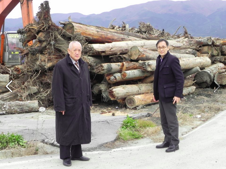 Nakazawa (right), with piles of wood for tsunami violins, illustrating the cross-cultural contributions on the path to healing (Image courtesy of Classic for Japan Foundation)