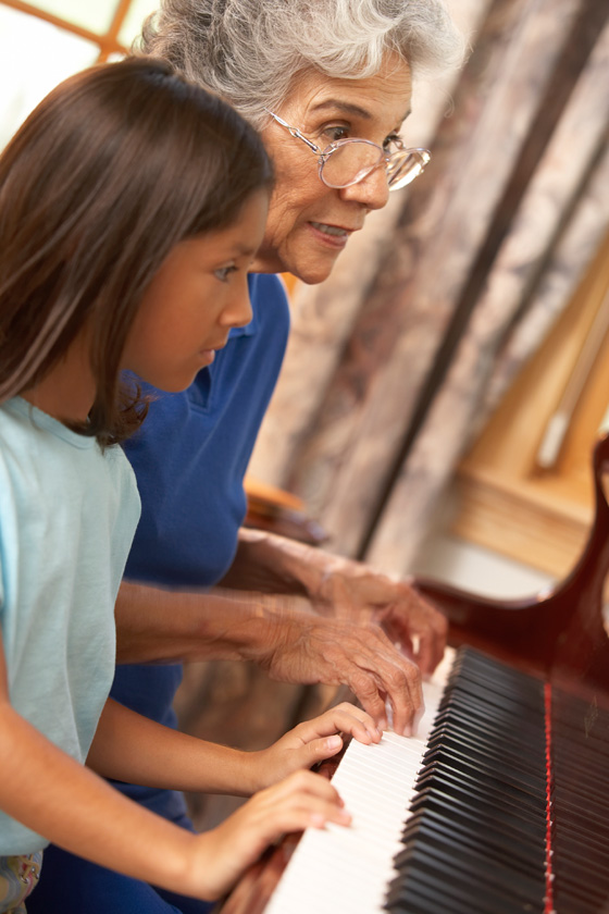 Grandmother teaching her granddaughter to play the piano, illustrating the best kind of gift-gving. (Image © Jack Hollingsworth / Photodisc)