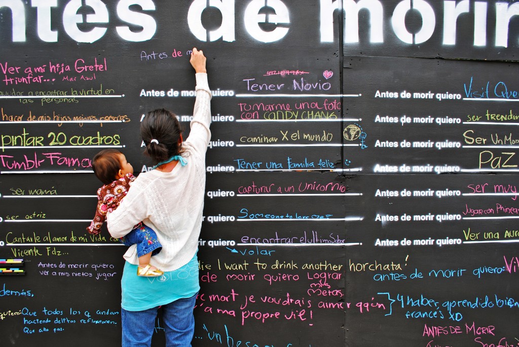 Mother reaching high to write on a "Before I die" wall in Querétaro, Mexico. Image © Candy Chang.