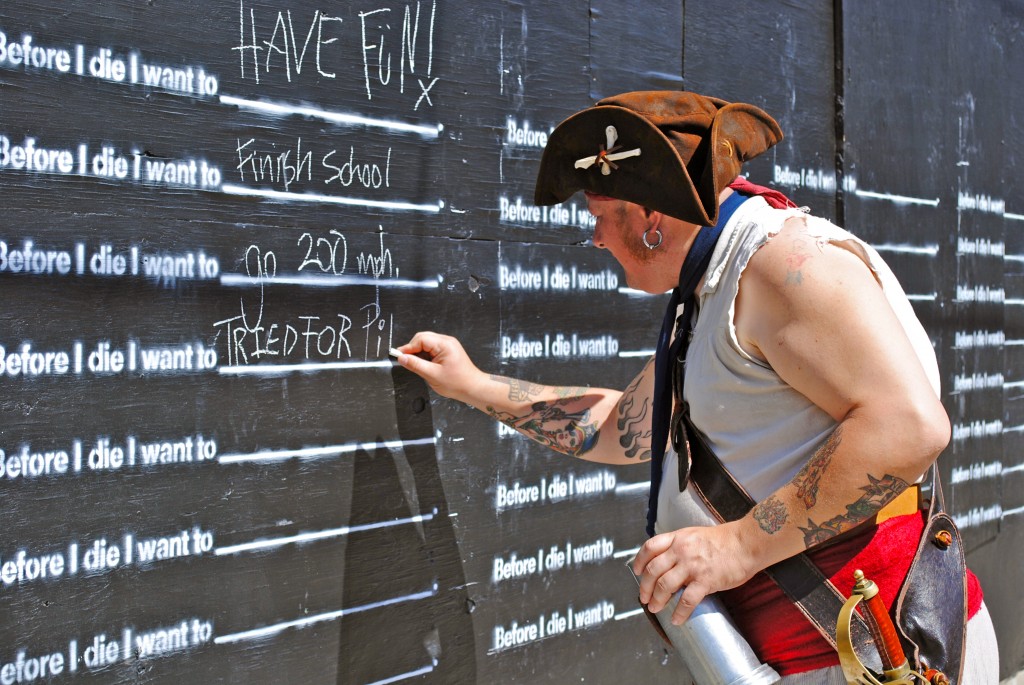 Man writing on the New Orleans "Before I die" wall. Image © Kristina Kassem.