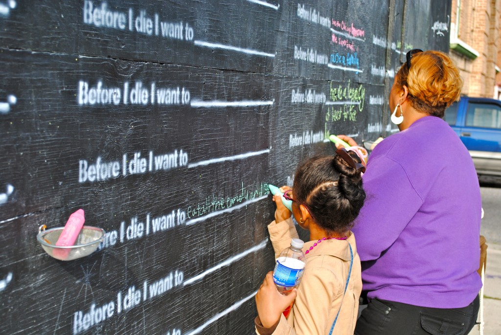 Mother and daughter writing on the "Before I die" wall in New Orleans. Image © Kristina Kassem.