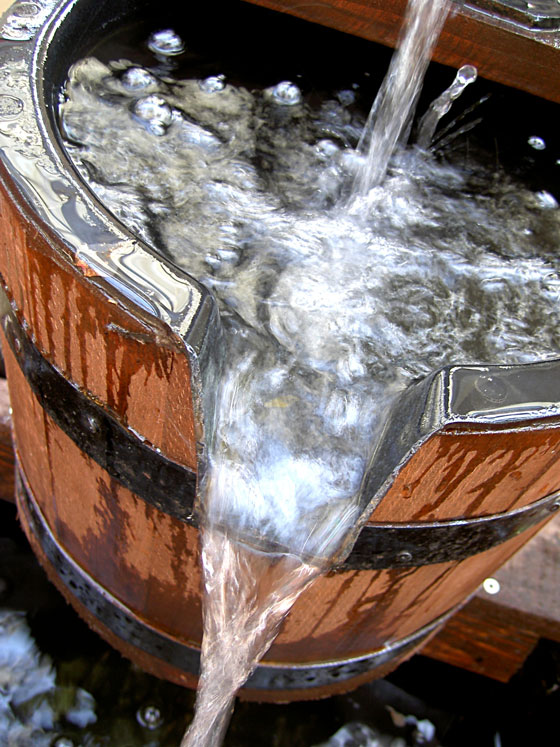 Barrel with water pouring out, illustrating the use of containers in rain sayings from different languages. (Image © Dawn Hudson / iStock)