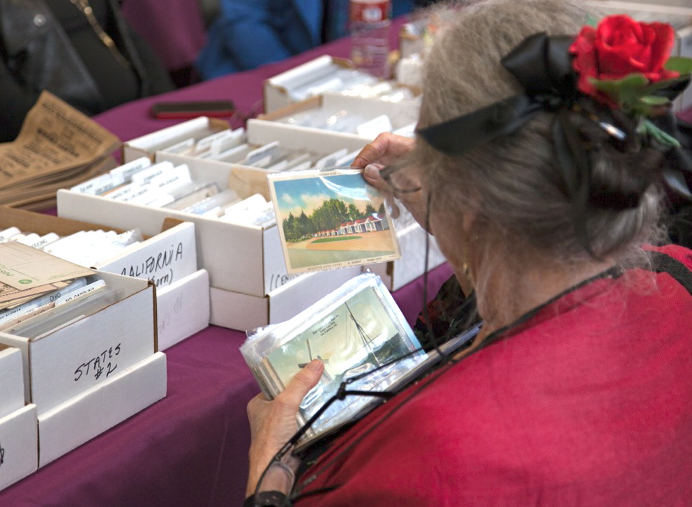 Woman searching through vintage postcards at a vintage paper fair where she is collecting ephemera. (Image © Erick Paraiso)