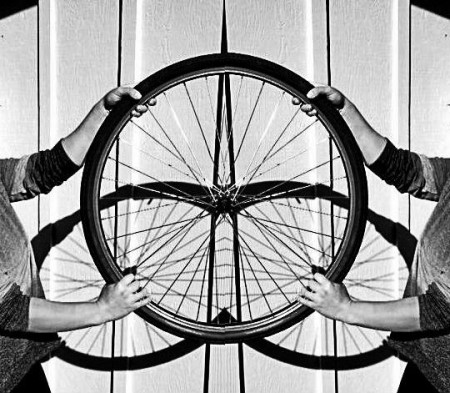 Two people holding up a bicycle wheel, illustrating how people in a bike co-op come together in a cyclist movement. (Image © Eva Boynton)