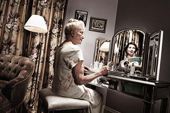 Elegant older woman sees a younger self reflected in mirror, one of a series of creative pictures by Tom Hussey on aging. (Photo © Tom Hussey)