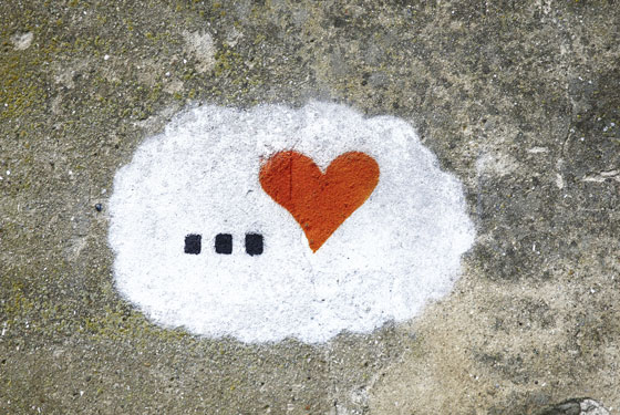 Ellipsis and heart painted on a sidewalk, illustrating love quotes on Valentine's Day about how the tough times can lead to a rock-solid relationship with your special someone. (Image © edelweiss7227 / iStock)