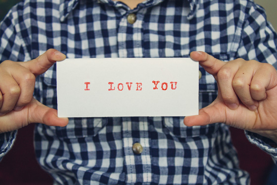 Man holding a sign saying "I love you," symbolizing a message and love quotes for Valentine's Day. (Image © © Ashley Matheny)