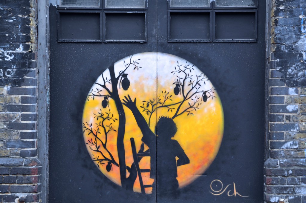 Creative street art in which a young child looks like he is picking fruit from a tree, but the fruit is really hand grenades. (Photo © Sheron Long)