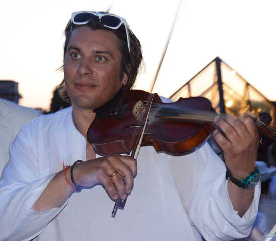 A Dîner en Blanc violinist at the Louvre in Paris, a way to live life to the fullest (Photo © Meredith Mullins)