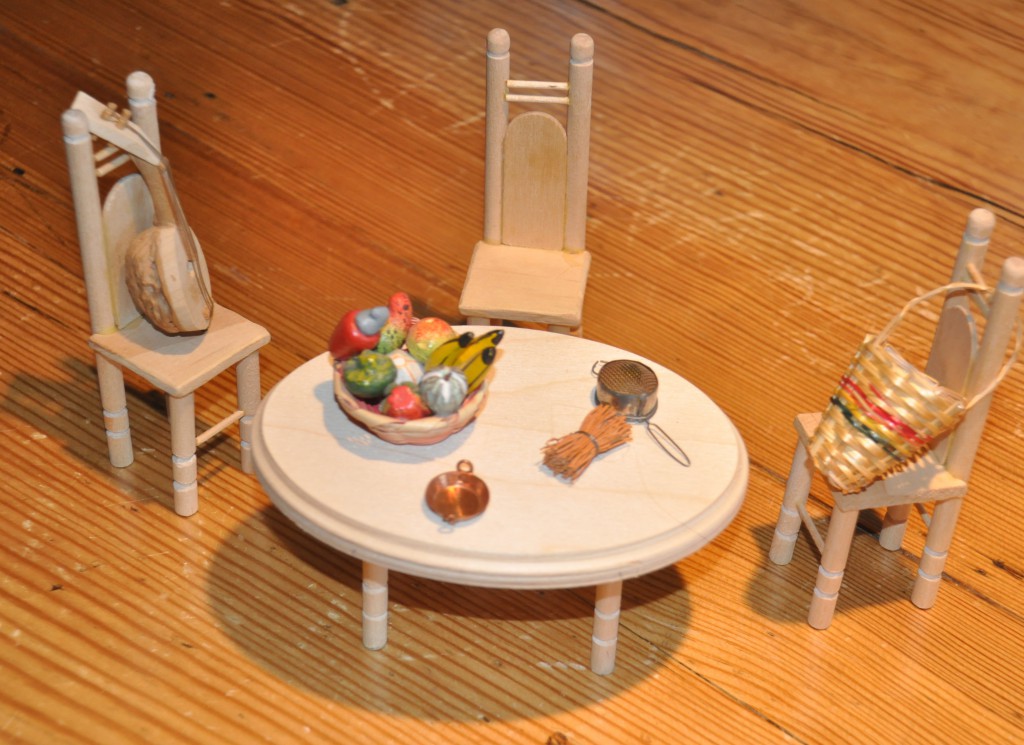 Miniature table set with a tiny basket of fruit and other household items, symbolizing the value of family time in Mexican culture. (Image © Sheron Long)