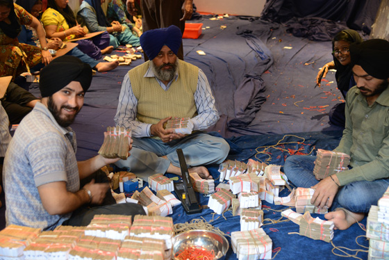 Sikhs counting donation money at the Sikh Temple in Delhi, cultural encounters in Northern India that provide travel inspiration. (Image © Meredith Mullins)