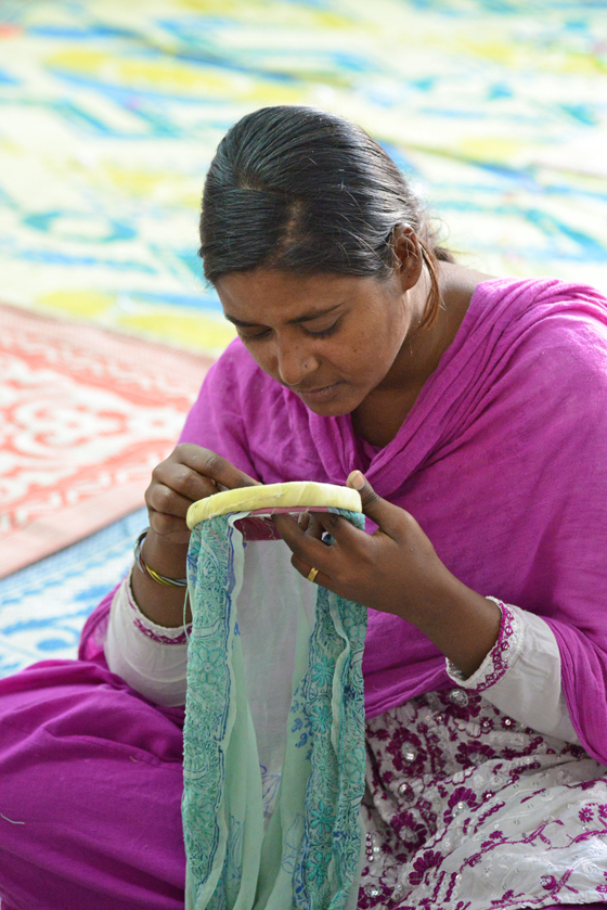 Woman in pink embroidering at SEWA, cultural encounters in Northern India that provide travel inspiration. (Image © Meredith Mullins)