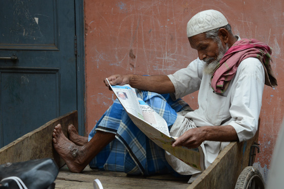 Man reading paper in Old Delhi, cultural encounters in Northern India that provide travel inspiration. (Image © Meredith Mullins)