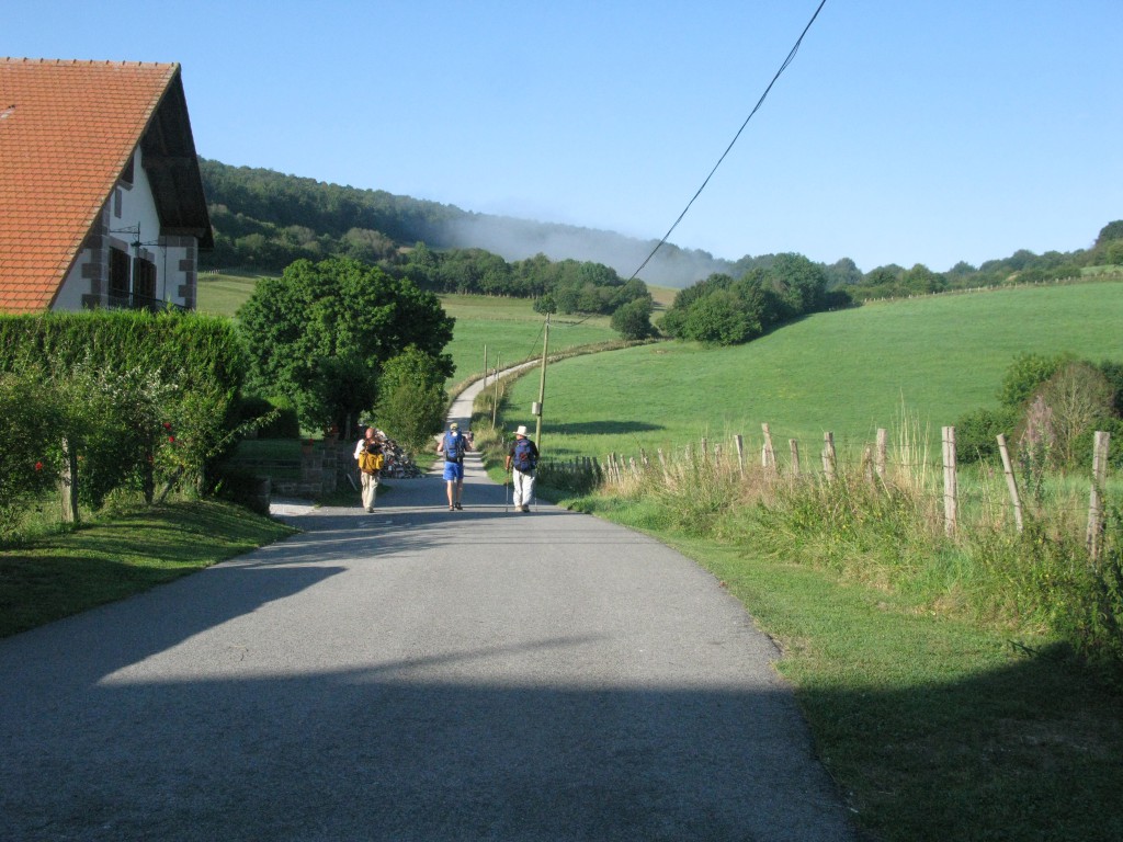 Three pilgrims walking down a road along the Camino de Santiago, each showing a personal travel inspiration for making the journey. (Image © Eva Boynton)