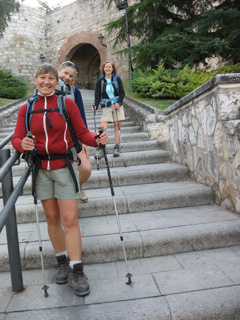 Three female pilgrims with backpacks and walking sticks following their person al travel i inspiration to walk the Camino de Santiago. (Image © Jenna Tummonds)