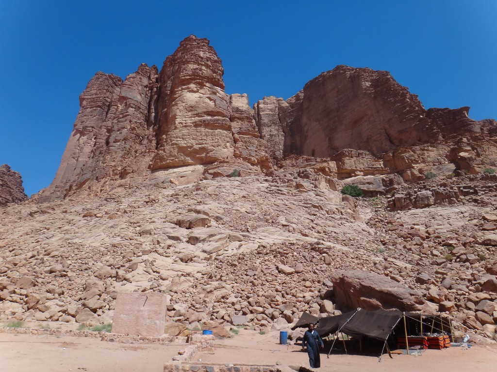 A Bedouin man and a tent set in front of a jagged butte in Wadi Rum, Jordan.  Sharing coffee in his tent, we bridged our cultural barriers. (Image © Sally Baho)