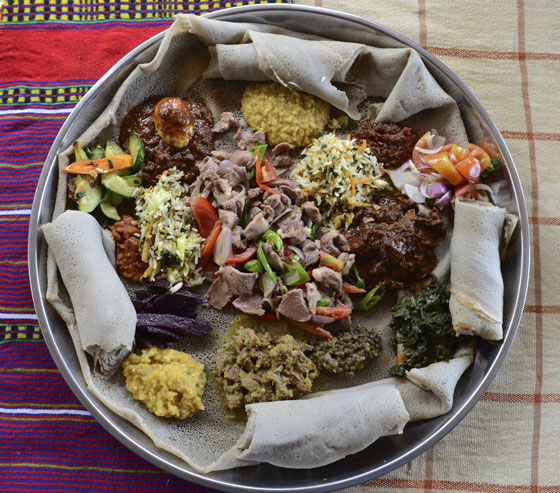 A traditional Ethiopian meal served on injera bread, illustrating different cultural do's and taboos at lunch around the world. (Image © Tendur / iStock)