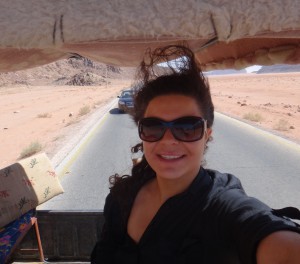 A girl iwith wind-blown hair in an open-air jeep on a trip that bridges cultural barriers in Wadi Rum, Jordan. (Image © Sally Baho)