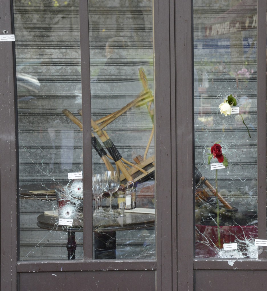 Bullet holes at one of the restaurants in the Paris attacks, with flowers showing the spirit of French cultural beliefs. (Image © Meredith Mullins.)