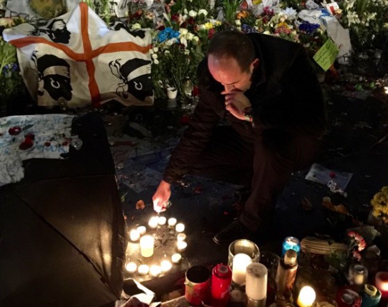 Man lighting candles after the Paris attacks, showing the spirit of French cultural beliefs. (Image © Jerry Fielder.)