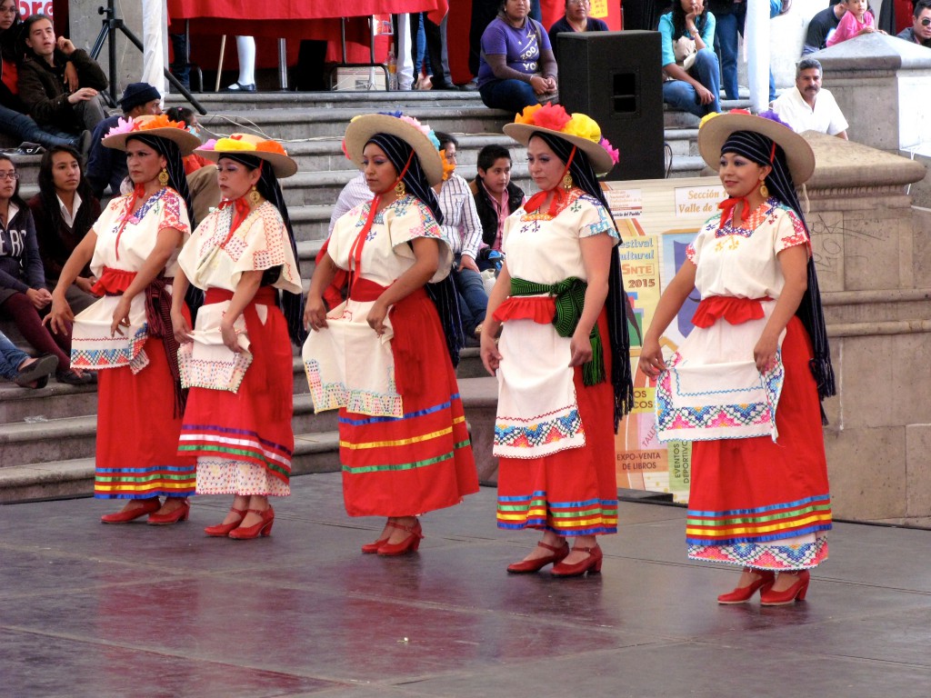 Women dressed in red dresses and hats for a traditional Mexican dance, showing Mexican tradition. (image © Eva Boynton)