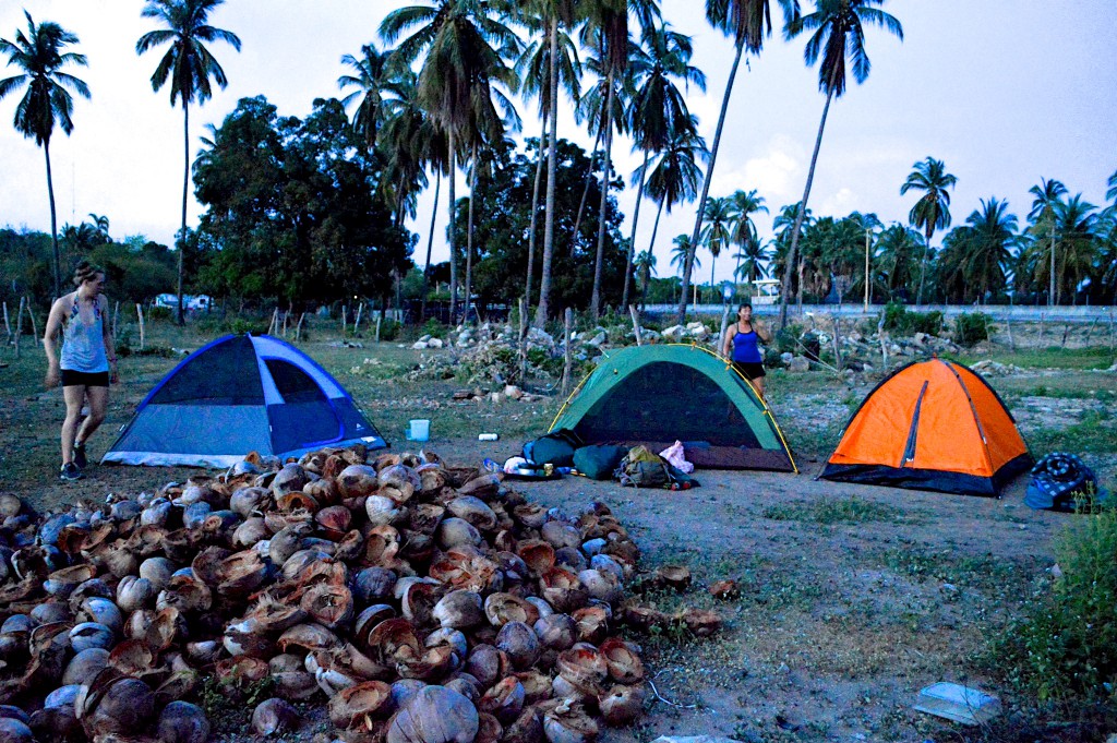 Three tents set up on a space on the side of a highway, illustrating how a good place to camp is a survival essential during adventure cycling along Mexican toll roads. (Image © Gabriela Díaz Cortez).