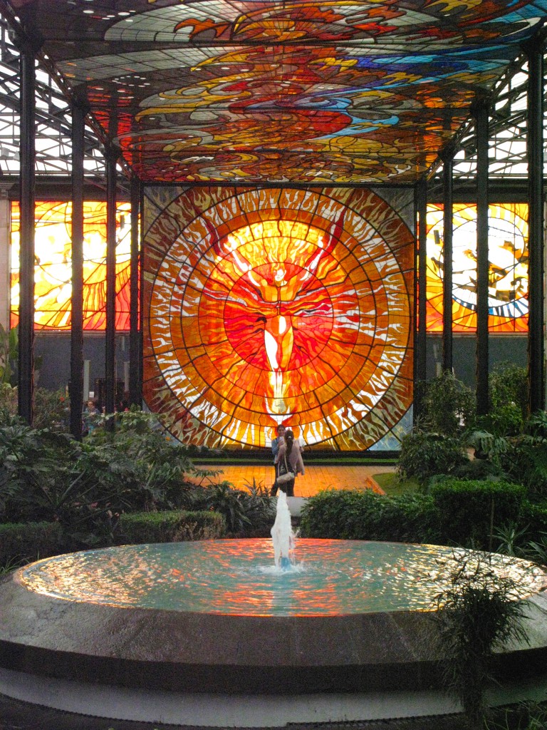 Stained glass of man with red orange colors at the Cosmovitral, a botanical garden and traveler's oasis in Toluca, Mexico. (Image © Eva Boynton)