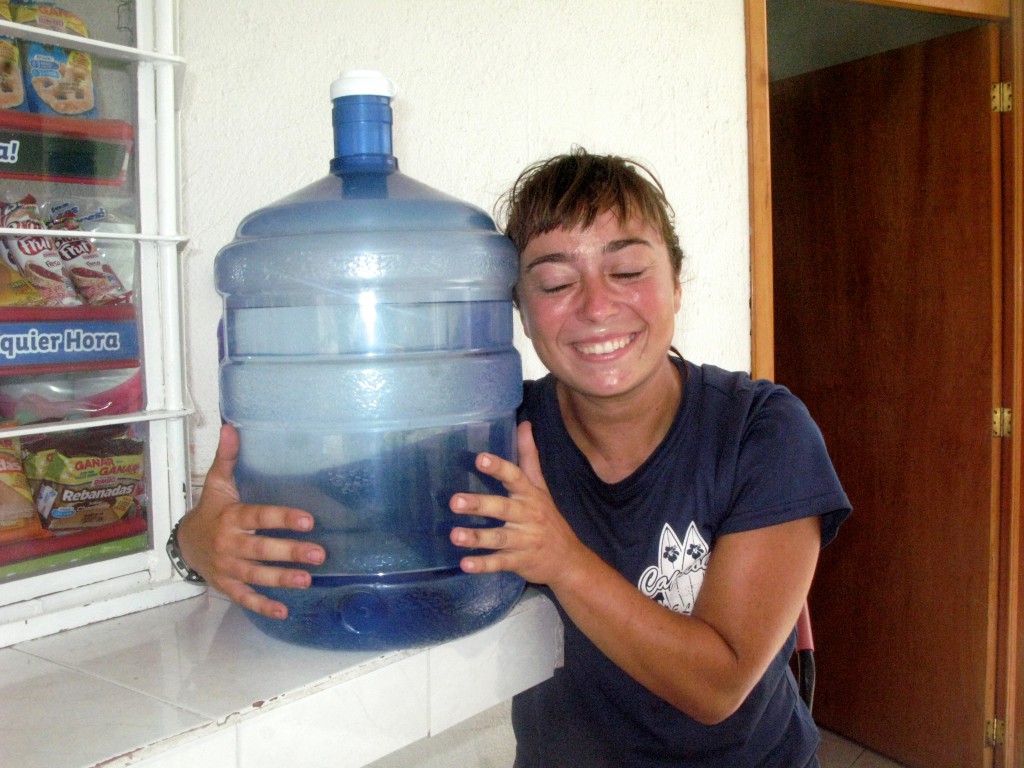 Woman hugging a gallon of water, showing the appreciation of a survival essential during adventure cycling on Mexican toll roads. (Image © Eva Boynton)