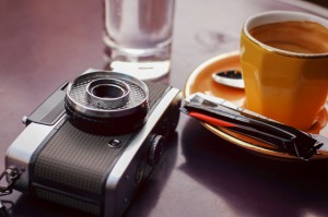 A vintage camera, water glass, and coffee cup, illustrating how savoring the moment can help people see things differently. (Image © pia–ch/iStock)