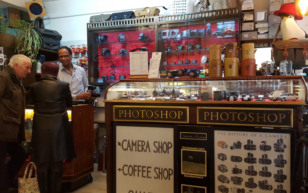 Customers checking out photography gear at the Camera Museum, part of London’s coffee culture and a place to slow down and see things differently. (Image © Camera Museum)