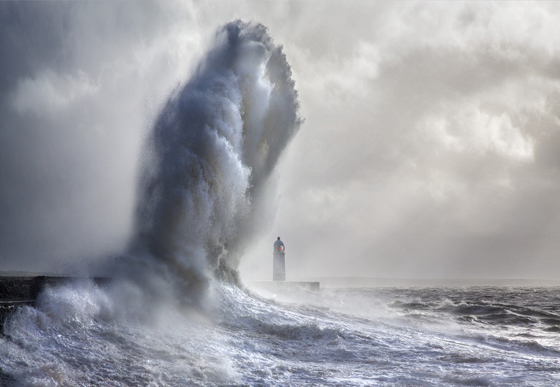 Hand-like wave threatening the Porthcawl lighthouse, showing one of the most amazing places on earth to photograph. (Image © Steven Garrington.)