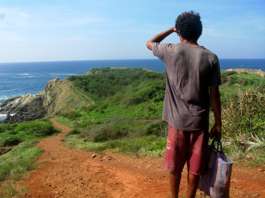 The local fisherman, who gave us fishing lessons, walks down a trail to his favorite fishing spot near Mazunte, Mexico, the site of an authentic cultural experience that enhanced the writer's travel memories (image © Eva Boynton).