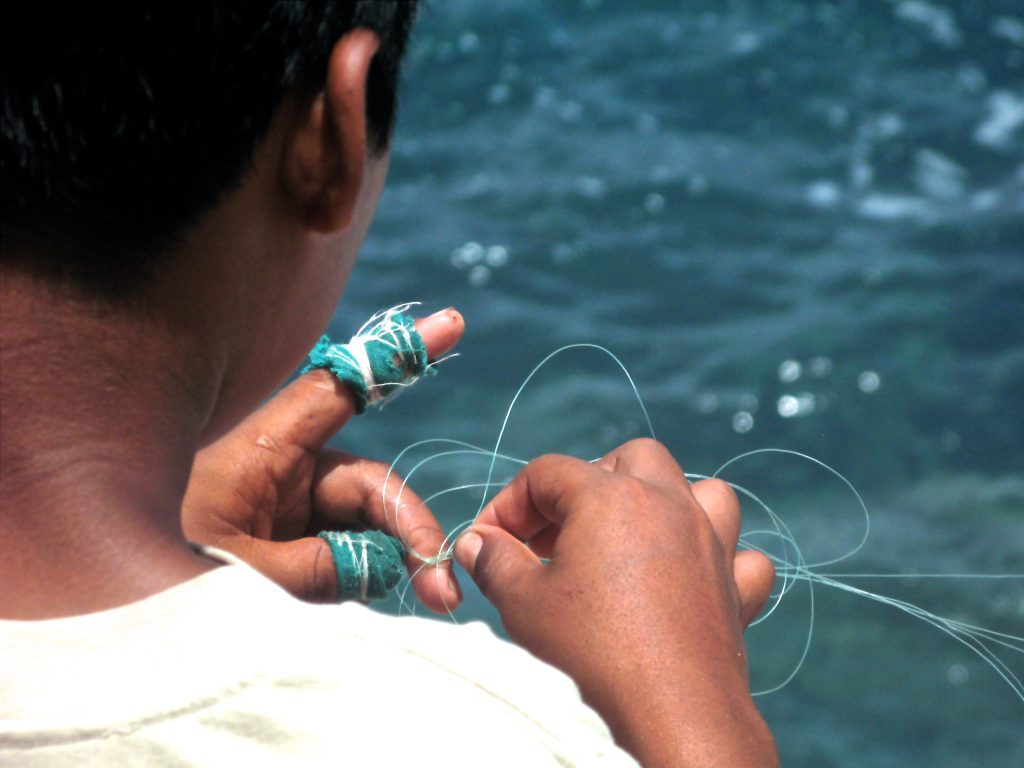A boy untangling fishing line as he offers fishing lessons during an authentic cultural experience in Mexico. (image © Eva Boynton).