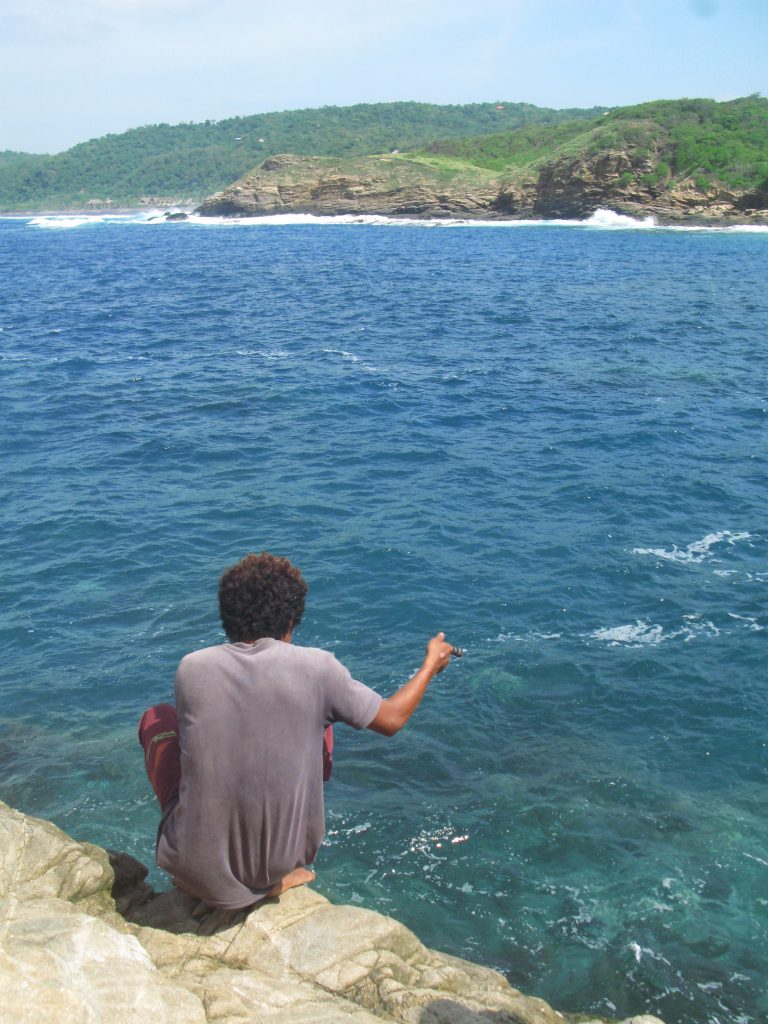 A local fisherman gives us fishing lessons as he demonstrates setting a fishing line free from the rocks and teaches the writer a lesson during an authentic cultural experience in Mexico. (image © Eva Boynton).