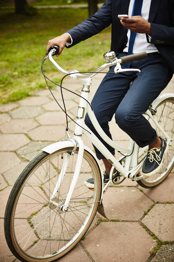 Businessman on bicycle texting, showing the language of social media and cultural changes. (Image © Shironosov/iStock.)