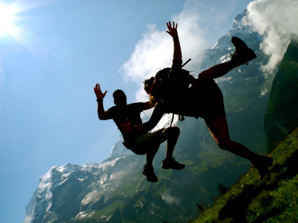 Two silhouettes of people jumping in the Alps of Switzerland, showing how traveling families take advantage of their inherited wanderlust (image © Eva Boynton)