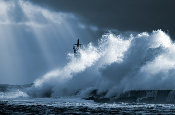 Ocean wave over lighthouse in North Portugal, one of the amazing places in the world to photograph. (Image © John North/iStock.)