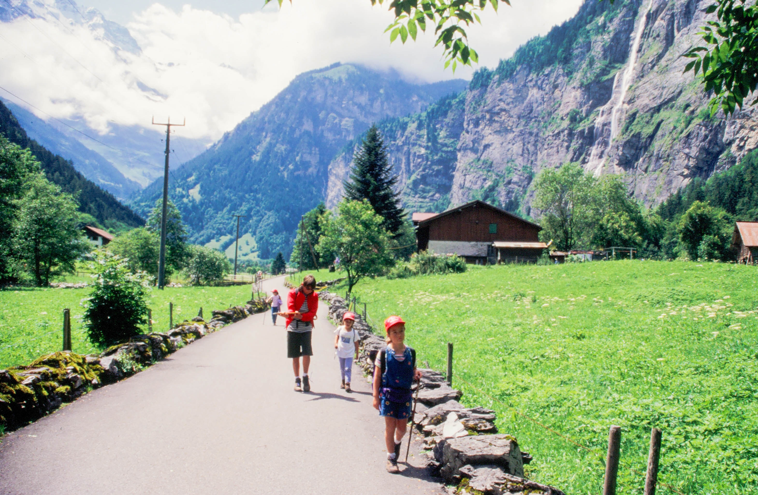 Three kids walking through a valley in Switzerland, illustrating how wanderlust is passed down in traveling families (image © Peter Boynton).